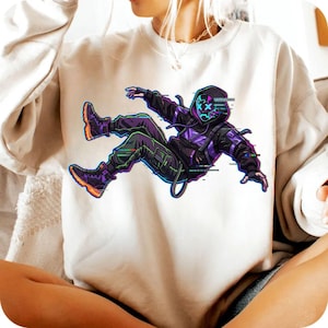 May include: A cream-coloured sweatshirt with a graphic of a person in a black and purple outfit and a neon mask. The illustration has glitch effects and orange accents on the shoes. The person is in a dynamic pose, suggesting movement.