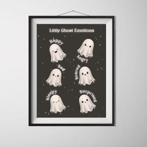 Könnte beinhalten: Ein gerahmter Druck mit dem Titel "Little Ghost Emotions" zeigt sechs Cartoon-Geister, die jeweils ein anderes Gefühl ausdrücken: glücklich, wütend, traurig, ängstlich, schläfrig und überrascht. Die Geister sind weiß auf einem dunkelgrauen Hintergrund.