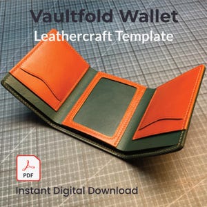 Op de afbeelding: Een opengevouwen trifold portemonnee van oranje en groen leer. De portemonnee heeft een doorzichtig ID-venster en kaartsleuven. De tekst "Vaultfold Wallet Leathercraft Template" en "Instant Digital Download" is zichtbaar.