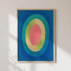 Könnte beinhalten: Ein rechteckiger Wandkunstdruck in einem hellen Holzrahmen mit einer Reihe konzentrischer ovaler Formen. Das Design besteht aus einem einfarbigen dunkelblauen Hintergrund, gefolgt von Ringen in Türkis, Hellgelb und einem rosa Oval in der Mitte.