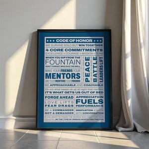 Könnte beinhalten: Ein gerahmtes Poster mit blauem Hintergrund und schwarzem Rahmen. Das Poster zeigt weißen Text mit Sätzen wie „Ehrenkodex“, „4 Kernverpflichtungen“ und „Führungskräfte heben“. Der Text ist vertikal und horizontal angeordnet.