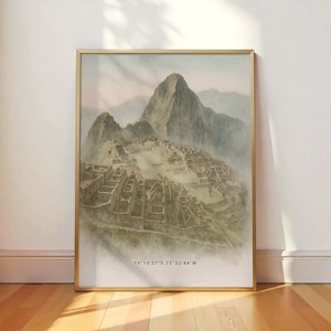 May include: A framed print featuring a watercolor painting of Machu Picchu, Peru. The artwork depicts the ancient city nestled in the mountains, with a misty atmosphere and a gold-colored frame. The coordinates 13°10'27"S 72°32'44"W are printed at the bottom.