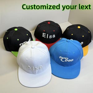 Könnte beinhalten: Eine Sammlung von Baseballkappen in verschiedenen Farben, darunter Schwarz, Weiß und Blau. Jede Kappe hat einen individuellen, gestickten Text in einer Kontrastfarbe. Der Text "Customized your lext" wird oben angezeigt.