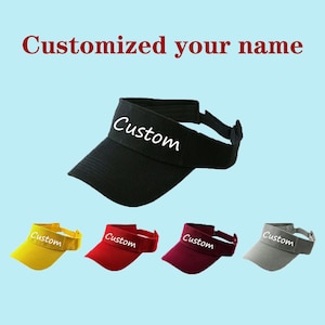 May include: Five visor hats in different colours: yellow, red, burgundy, grey, and black. Each hat has the word "Custom" embroidered on the front in white.