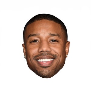 Puede incluir: Un primer plano de la cara de un hombre. Tiene el pelo corto negro, ojos marrones y una amplia sonrisa. Lleva un par de pequeños pendientes.