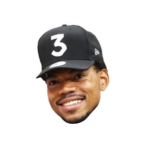 Peut inclure: Gros plan d'un homme portant une casquette de baseball noire avec un "3" blanc sur le devant. Il sourit et regarde vers la droite.