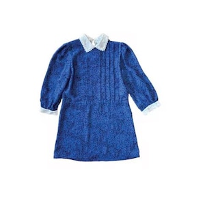 Könnte beinhalten: Ein blaues Kleid mit weißem Kragen und Manschetten. Das Kleid hat ein Muster aus kleinen dunkelblauen Punkten und Falten auf der Vorderseite. Die Ärmel sind dreiviertellang.