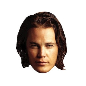 May include: A close-up portrait of a person with long brown hair. The person has a serious expression and is looking directly at the camera.