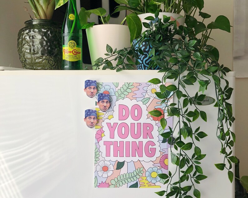 Pode incluir: Um refrigerador branco com um p&ocirc;ster que diz "Do Your Thing" em letras rosa. O p&ocirc;ster tem um design floral e tr&ecirc;s &iacute;m&atilde;s com o rosto de um homem.