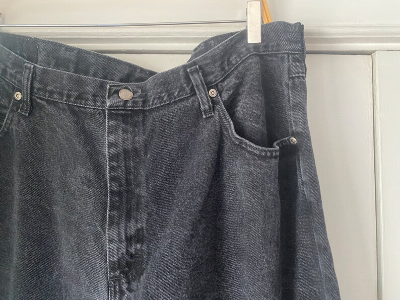May include: A pair of dark gray denim jeans with a single front pocket and a button closure.