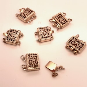 May include: Seven gold-toned metal clasps with a decorative floral design. Each clasp has three loops for attaching to a necklace or bracelet.