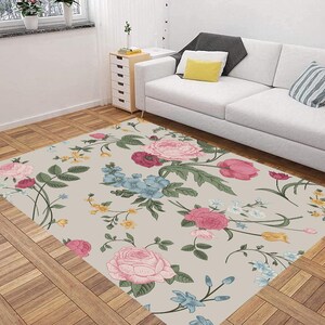 May include: A floral area rug with a light beige background and a repeating pattern of pink, red, yellow, blue, and green flowers. The rug has a vintage style and is perfect for adding a touch of elegance to any room.