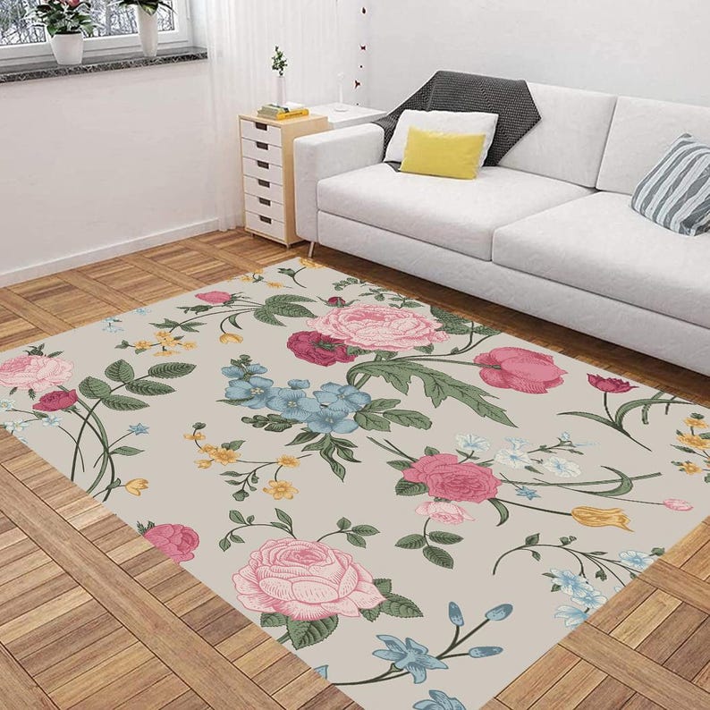 May include: A floral area rug with a light beige background and a repeating pattern of pink, red, yellow, blue, and green flowers. The rug has a vintage style and is perfect for adding a touch of elegance to any room.