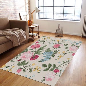 May include: A floral area rug with a cream background and pink, blue, and yellow flowers. The rug has a vintage floral pattern and is perfect for adding a touch of elegance to any room.