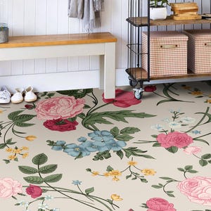May include: A floral patterned rug with pink, red, blue, and yellow flowers on a cream background. The rug is placed in a hallway with a white bench and a metal shelving unit with baskets on the shelves.
