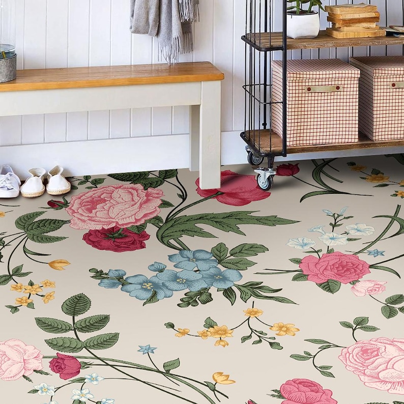 May include: A floral patterned rug with pink, red, blue, and yellow flowers on a cream background. The rug is placed in a hallway with a white bench and a metal shelving unit with baskets on the shelves.