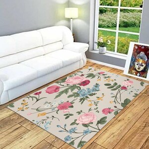 May include: A floral area rug with a light beige background and a repeating pattern of pink, red, blue, and yellow flowers. The rug is on a hardwood floor in a living room setting.