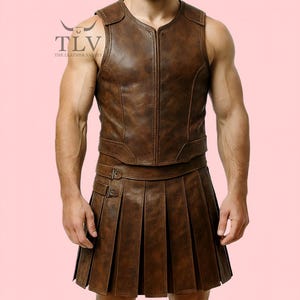 May include: Brown leather vest and pleated skirt set. The vest has a V-neck and a zip closure. The skirt is pleated with buckle details. The Leather Valley logo is visible in the upper left corner.