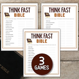 Może przedstawiać: Trzy drukowane arkusze gier z tekstem "THINK FAST BIBLE" i brązową grafiką książki. Gry znajdują się na drewnianej powierzchni z czarną Biblią i fioletowymi kwiatami. Widoczny jest również brązowy okrąg z napisem "3 GAMES".