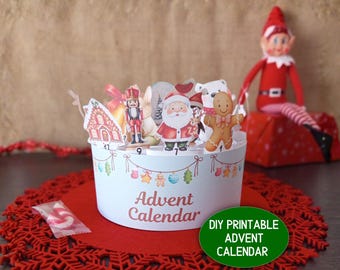 May include: A DIY printable Advent calendar with festive illustrations of Santa, a gingerbread man, and a nutcracker. The light blue calendar has the words "Advent Calendar" printed on the front. A red elf doll sits in the background.