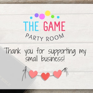 May include: A white card with the text "THE GAME PARTY ROOM" in colorful letters and a message: "Thank you for supporting my small business!" Three pink hearts hang below the message.
