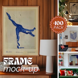 Op de afbeelding: Een ingelijste kunstprint met een blauwe abstracte schildering en het woord "BLEU" in de linkerbenedenhoek. De lijst hangt aan een houten muur met een witte lamp en een stapel boeken op een tafel eronder.