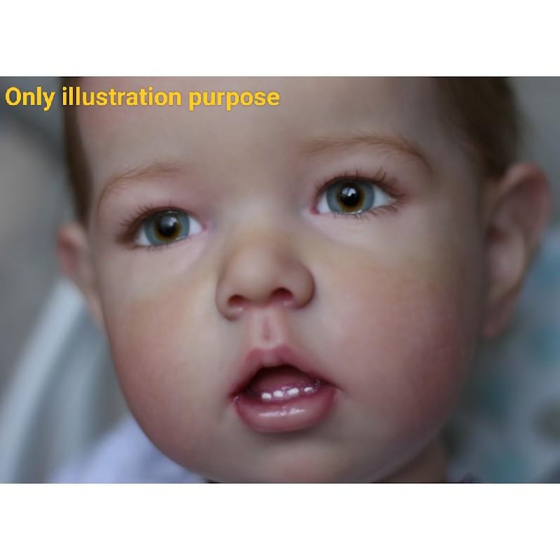 Puede incluir: Primer plano de una mu&ntilde;eca beb&eacute; realista con ojos azules y boca rosa claro. La mu&ntilde;eca tiene un tono de piel suave y lisa y est&aacute; mirando hacia arriba.