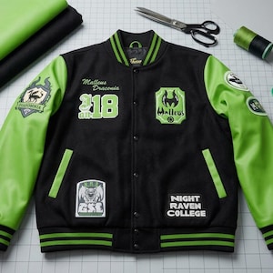 Puede incluir: Chaqueta universitaria negra y verde con parches. La chaqueta tiene mangas y ribetes verdes, con el texto "Night Raven College" y otros parches. Los suministros de costura están dispuestos alrededor de la chaqueta.