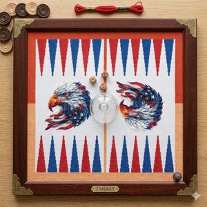 May include: A square wooden backgammon board with a dark brown frame and brass corner accents. The playing surface features a white fabric background with red and blue points, two embroidered eagle heads, two wooden dice, and a clear plastic cup.
