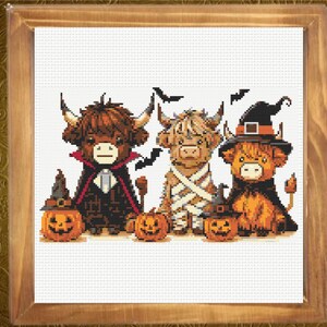 May include: A cross-stitch pattern featuring three Highland cows dressed for Halloween. One cow wears a vampire cape, one is wrapped like a mummy, and one wears a witch hat. Three jack-o'-lanterns sit in front of them, and black bats fly above.