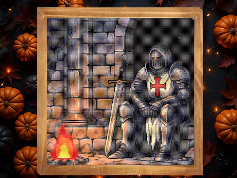 Puede incluir: Obra de arte de punto de cruz en un marco de madera que representa a un caballero con armadura completa, sentado con una espada. El caballero tiene una cruz roja en el pecho. Un peque&ntilde;o fuego arde cerca. El fondo es una pared de piedra. Calabazas y hojas de oto&ntilde;o rodean el marco.