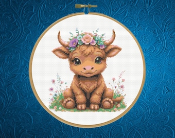 May include: A cross-stitch pattern in a round wooden embroidery hoop featuring a brown Highland calf with large eyes, wearing a colourful floral crown of pink, purple, and blue flowers, sitting on a patch of green grass with small wildflowers.
