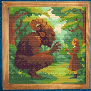 Op de afbeelding: Kruissteekkunst van een fantastische scène. Een groot, gehoornd wezen knielt voor een meisje in een bosrijke omgeving. Het kunstwerk is ingelijst in een houten lijst, met een kleurenpalet van groen, bruin en oranje.