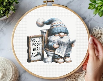 May include: A cross-stitch pattern in a wooden embroidery hoop featuring a gnome wearing a blue hat and white beard, sitting on a toilet reading a newspaper. Next to the gnome is a sign with the text WOULD POOP HERE AGAIN and a roll of toilet paper.