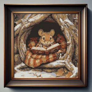 May include: A framed cross-stitch embroidery depicting a small brown mouse sitting inside a hollow tree trunk. The mouse is wrapped in a striped orange and brown blanket while reading an open book. The scene includes snowy details and a mushroom.