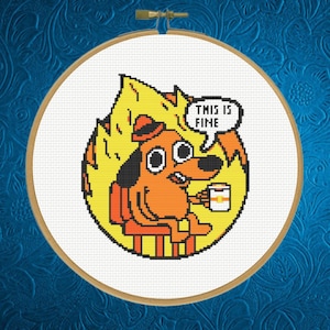 May include: Cross-stitch of the "This is Fine" meme, depicting a dog in a burning room, holding a mug. The text "THIS IS FINE" appears in a speech bubble. The dog is orange and black, with yellow flames surrounding it. The hoop is round.