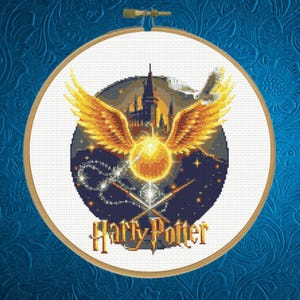 May include: A circular cross-stitch embroidery in a wooden hoop featuring a golden snitch with large wings, a dark castle silhouette, a white owl, and two crossed wands. The text Harry Potter is stitched in yellow at the bottom against a dark blue night sky.