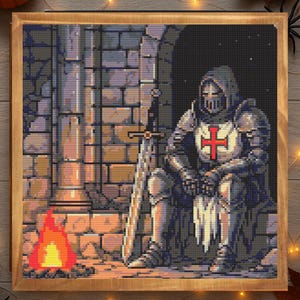 Puede incluir: Imagen de punto de cruz de un caballero con armadura completa, sentado con una espada, cerca de una peque&ntilde;a hoguera. El caballero tiene una cruz roja en el pecho. El fondo es una pared de piedra. La obra est&aacute; enmarcada.