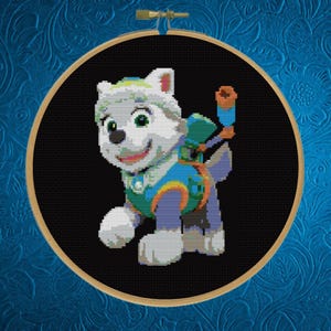 May include: A cross-stitch embroidery piece featuring a white puppy character with green and blue gear, including a backpack and a telescope, set against a solid black background and framed within a circular wooden embroidery hoop.