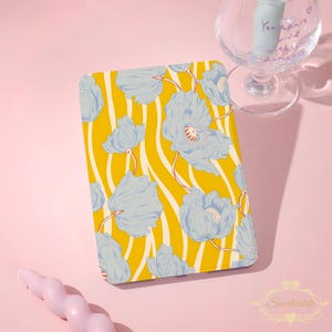 May include: A rectangular e-reader cover featuring a vibrant yellow background with white wavy vertical stripes and a repeating pattern of light blue poppy flowers. The cover is positioned next to a clear glass goblet and a pink spiral candle.
