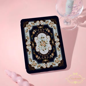 May include: A navy blue tablet case featuring a floral rug design. The case has a light blue center with a floral pattern in peach and green. The border is navy blue with gold accents. The Suchakk logo is in the bottom right corner.