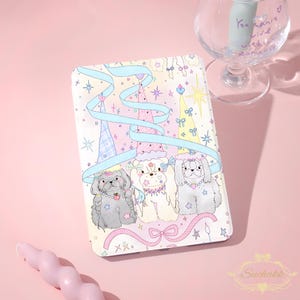 May include: A rectangular tablet case featuring a pastel illustration of three fluffy dogs wearing party hats, adorned with blue ribbons, stars, and hearts. The design includes a light pink background with decorative bows and sparkles.