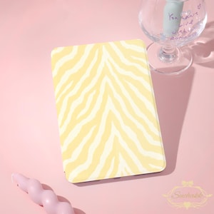 May include: A rectangular tablet case featuring a pale yellow and white zebra stripe pattern. The case has a smooth, flat surface and rounded corners, displaying a consistent animal print design across the entire front-facing exterior panel.