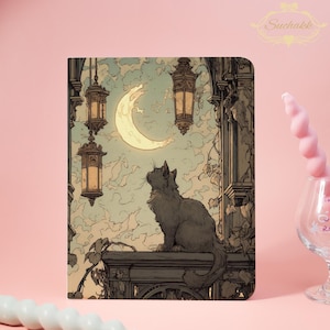 May include: Notebook featuring a detailed illustration of a black cat gazing at a crescent moon in a night sky. The artwork includes hanging lanterns and architectural details, with a vintage aesthetic. The Suchakk logo is in the upper right corner.