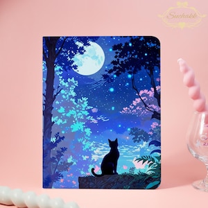 May include: A notebook with a fantasy illustration of a black cat silhouetted against a moonlit forest scene. The artwork features a full moon, starry sky, and trees with blue and pink foliage. The Suchakk logo is in the upper right corner.