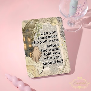 May include: A rectangular print featuring a collage of vintage newspaper text, a ghost illustration, a building, a planet, a sun, and flowers. The text reads: Can you remember who you were, before the world told you who you should be? The design uses sepia tones.