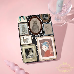 May include: A rectangular tablet case featuring a black background with white line art and multiple framed cat portraits. The images include various cat breeds in ornate frames, including one cat wearing a headscarf reminiscent of a classic painting.