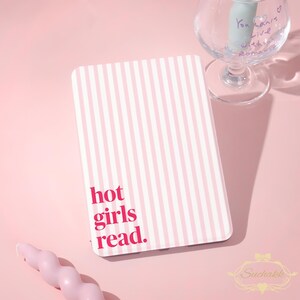 May include: A rectangular e-reader case featuring a vertical light pink and white striped pattern. The text "hot girls read." is printed in a bold, dark pink sans-serif font in the lower left corner of the front cover of the protective case.