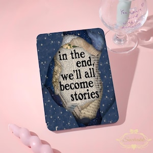 May include: A rectangular e-reader case featuring a dark blue starry night sky design that appears to be torn open to reveal a vintage newspaper background with the black text: in the end, we'll all become stories. The case has a smooth finish.