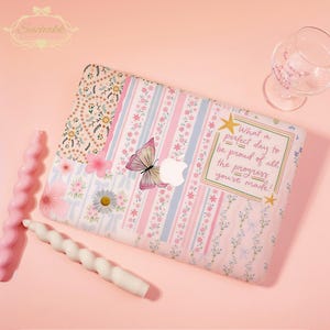 May include: A laptop skin featuring a patchwork design of pink, blue, and white floral patterns, stripes, and bows. A butterfly graphic is centered near the Apple logo. A rectangular box contains the text: What a perfect day to be proud of all the progress you've made!